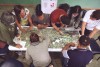 A top-down view of a group of 8 people stood around a table, annotating maps together thumbnail