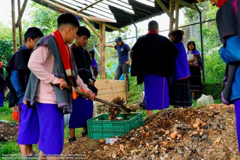 Participants of the agroecology course work together to build up compost piles using leaves and other organic material