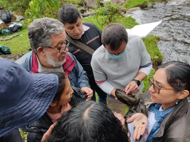 Hub and ASOCAMPO members gather together to observe and discuss material samples taken from the Cauca River as part of a water quality monitoring exercise