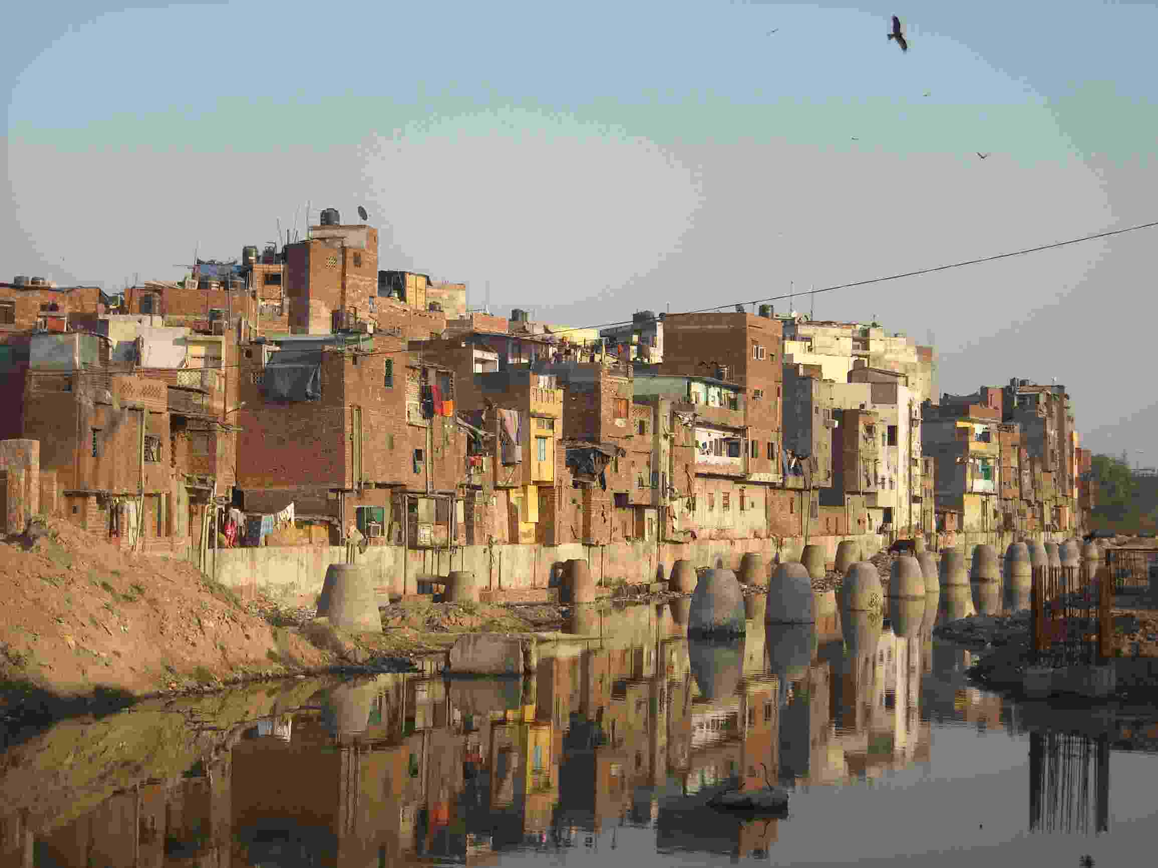 Image shows an informal settlement on the water's edge in Delhi