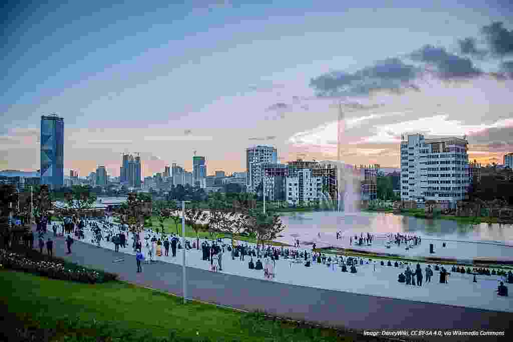 Addis Ababa skyline as seen from a green hill in Sheger Park, with a large water fountain visible in the foreground and rising skyscrapers behind