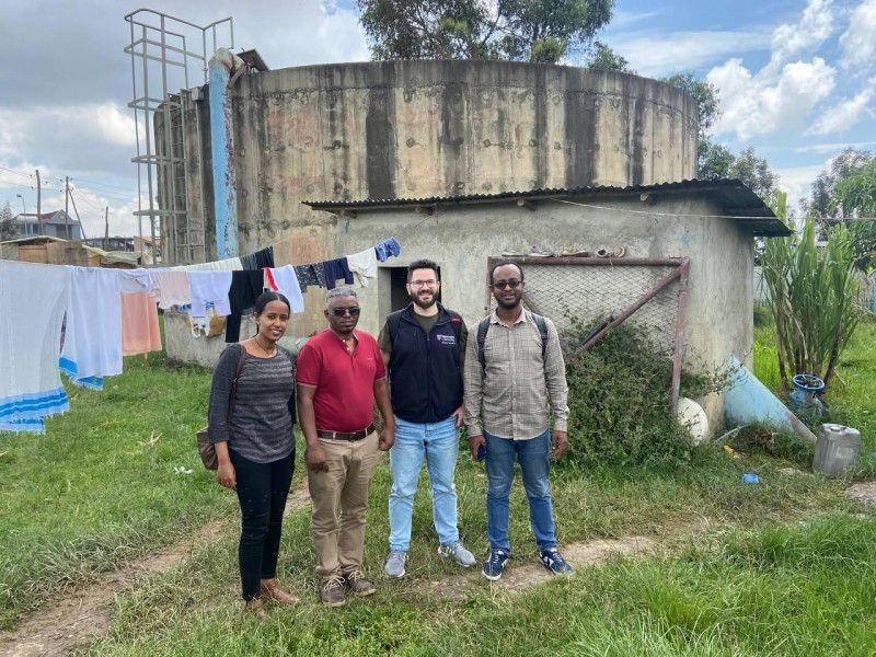 Four Hub colleagues stood on green grass in front of a concrete water storage facility