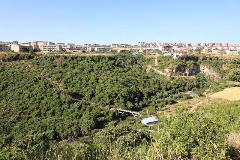 The river flows away from Addis Ababa, with banks covered in greenery and plants and topped with many residential buildings on either side