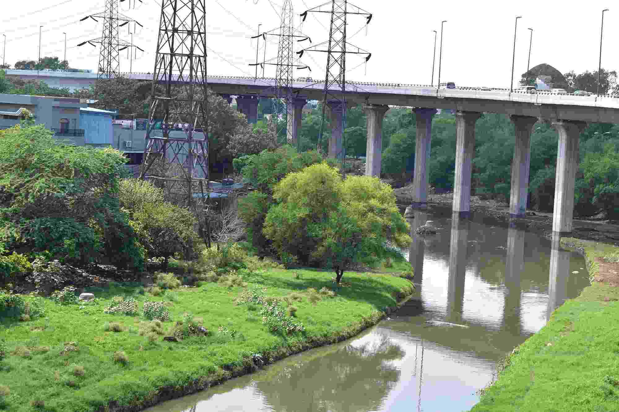 The Barapullah Drain is a key but polluted part of Delhi's drainage system, seen here with a large bridge crossing it and several electricity pylons located around it