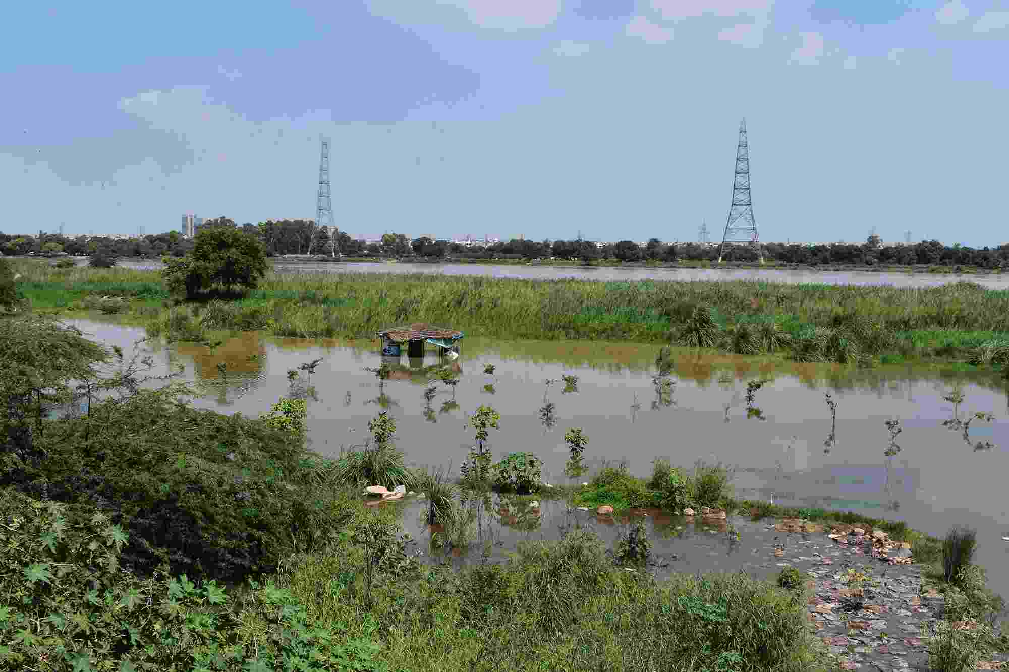 The flood plains of the Yamuna covered with water, with electricity pylons visible in the distance