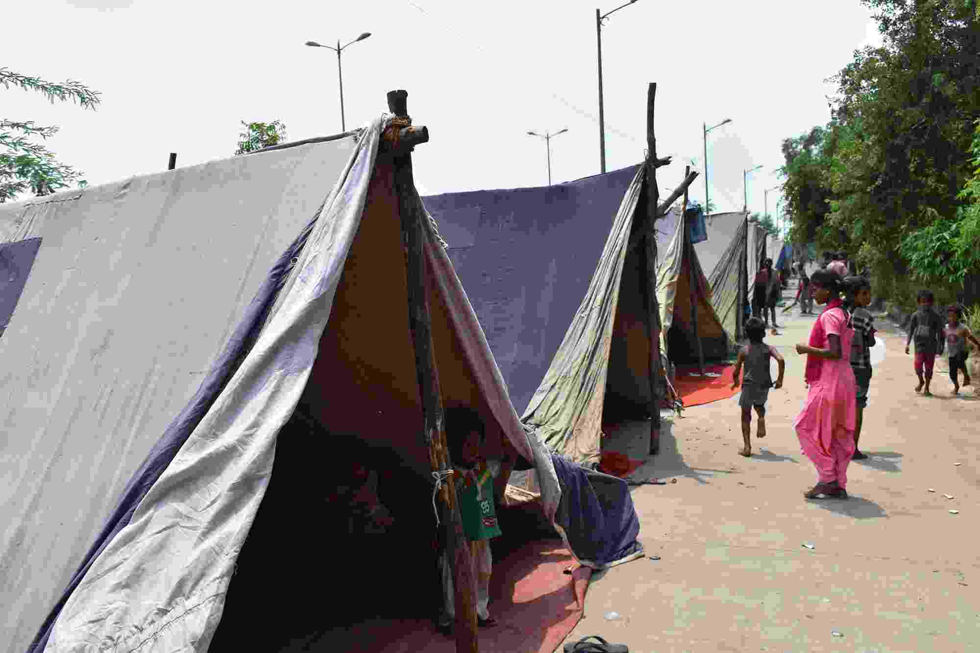 People wander past tents at the makeshift relief camp created because of the Yamuna flood in 2019, India