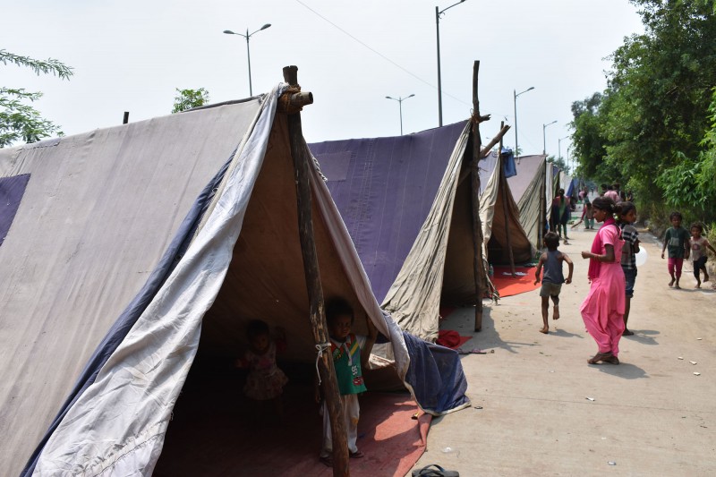 People wander past tents at the makeshift relief camp created because of the Yamuna flood in 2019, India