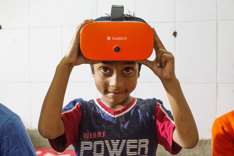 A young school pupil looks up as they prepare to use a virtual reality headset