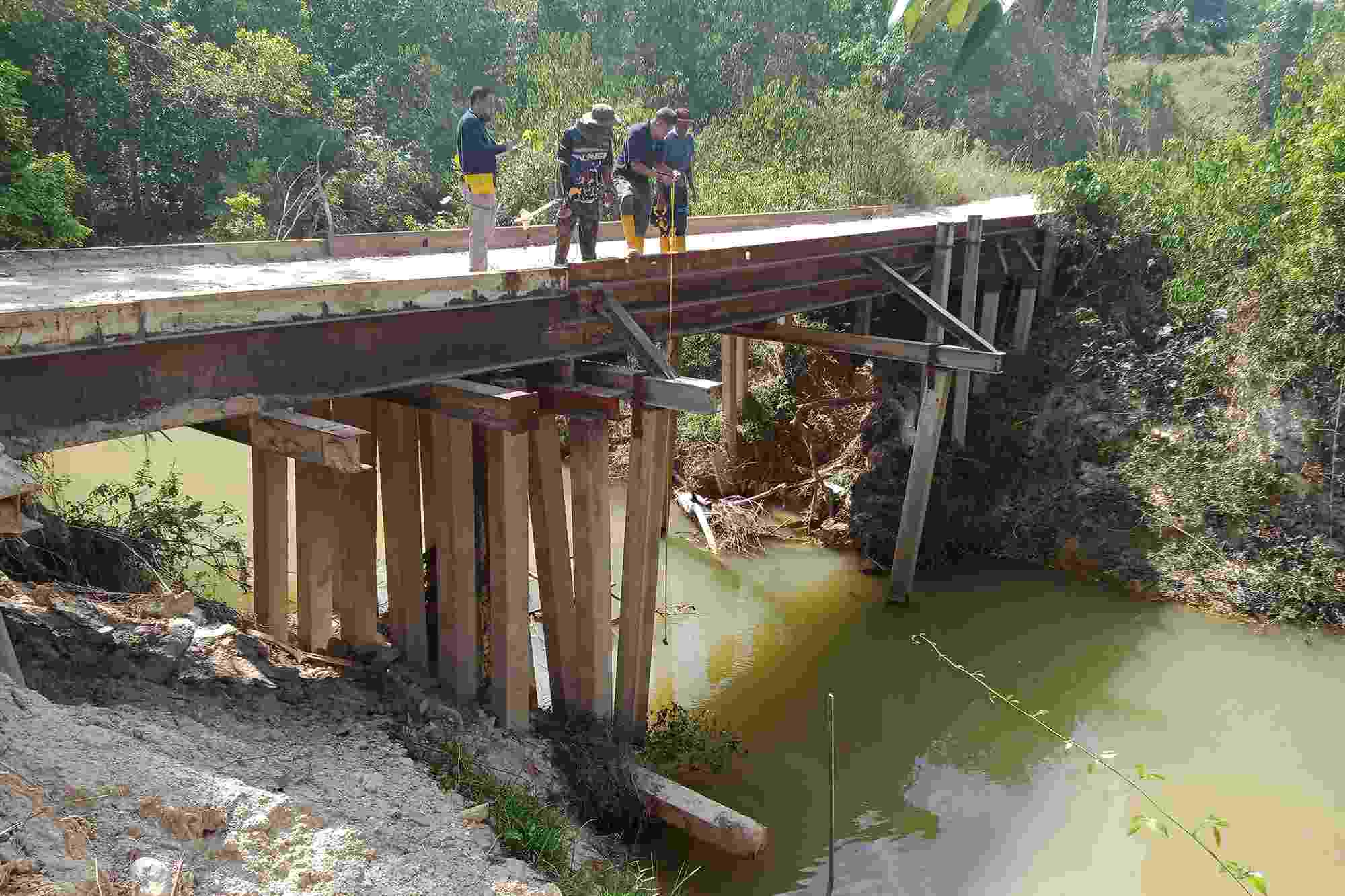 UTM colleagues lower equipment from a steel bridge into the river water below as part of Flowrate channel determination work