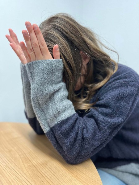 A side view of an actress sat at a table with her head in her hands