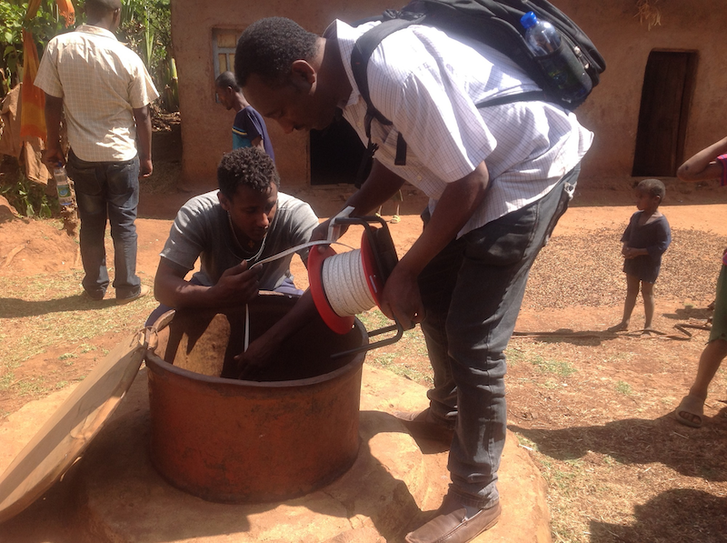 Image shows Hub researchers and citizen scientists using equipment to measure shallow groundwater in a well