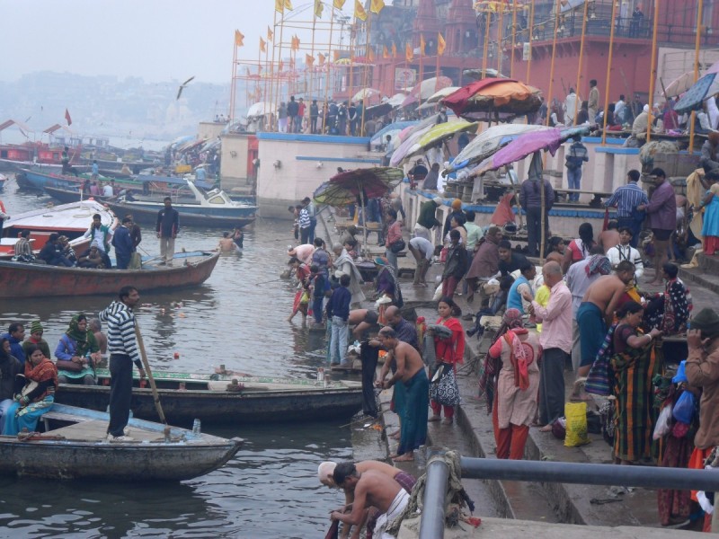 People selling food, washing clothes, bathing, and landing boats around one of the ghats on the banks of the River Ganges, Varanasi, India
