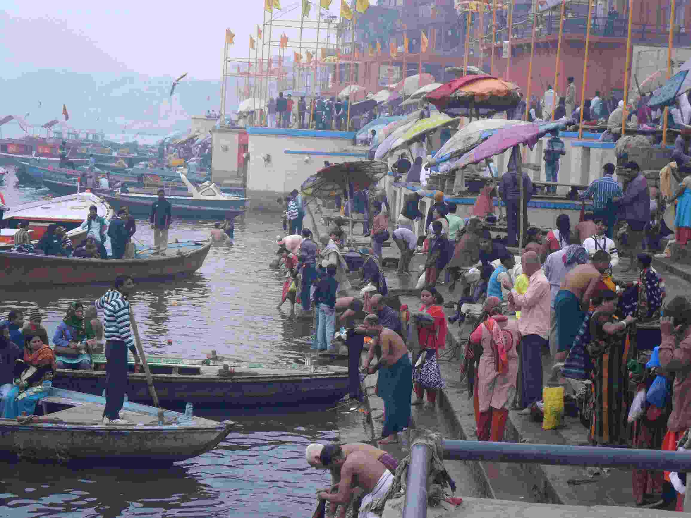 People selling food, washing clothes, bathing, and landing boats around one of the ghats on the banks of the River Ganges, Varanasi, India